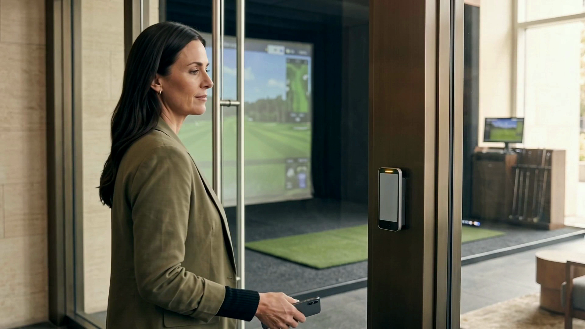 A tenant outside a golf simulator with a mobile phone and a door access reader